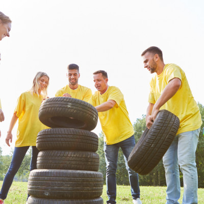 a group of people in yellow shirts with tires stacked on each other