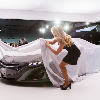 a woman in a black dress holding a white cloth over a car